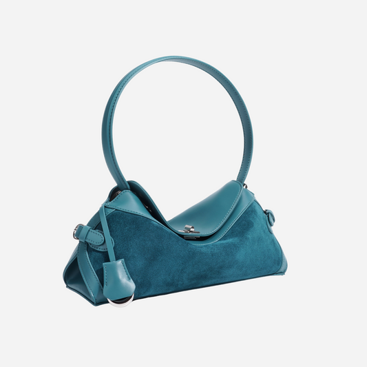 Teal handbag in suede and leather, angled view showing front and side with circular handle.